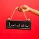 A hand holds a limited edition sign against a vibrant red background, perfect for marketing use.